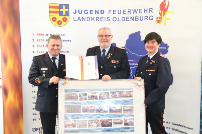Werner Mietzon (links) verlieh Peter Sparkuhl die Ehrennadel der Deutschen Jugendfeuerwehr in Gold. Diane Febert (links) überreichte eine Bildercollage. / Bild:Bahrs